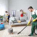 Professional homecare experts deep cleaning a living room by vacuuming rugs and cleaning furniture.